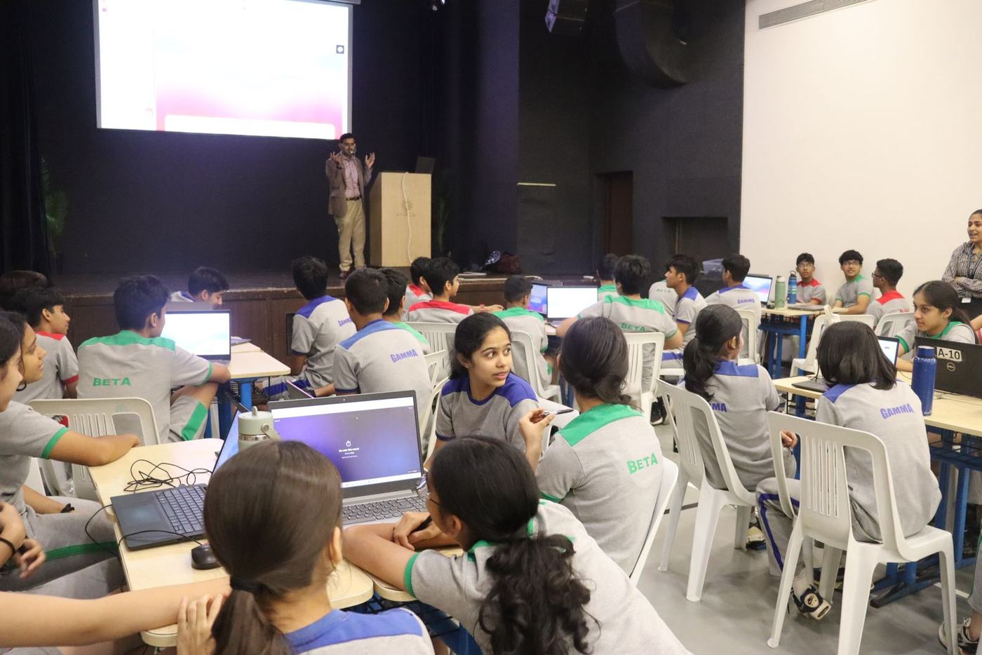 Students building on their laptops while Ali guides from the stage